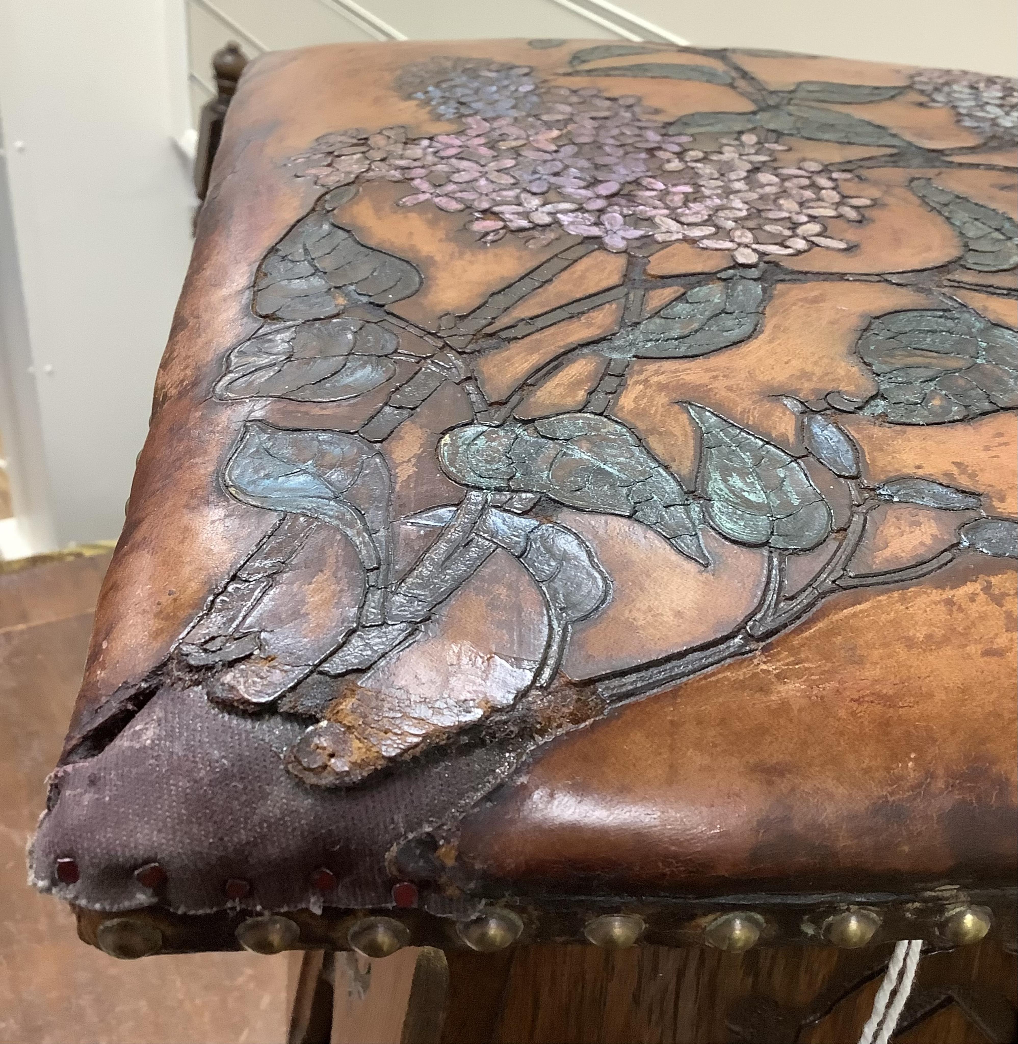 An early 20th century Liberty & Co. Arts & Crafts style stool with embossed leather seat, (later coloured), width 31cm, height 42cm. Condition - fair